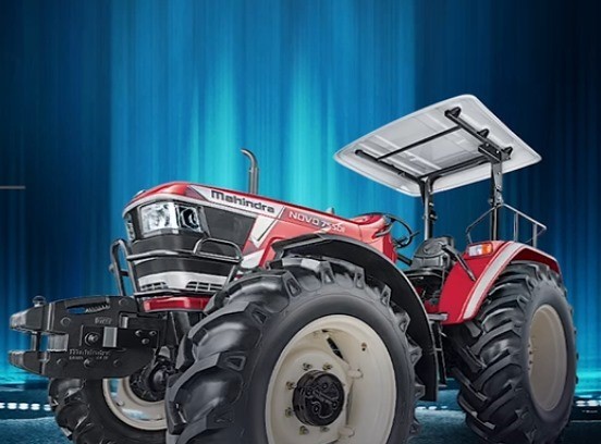 Mahindra Novo tractor plowing a large field at sunset